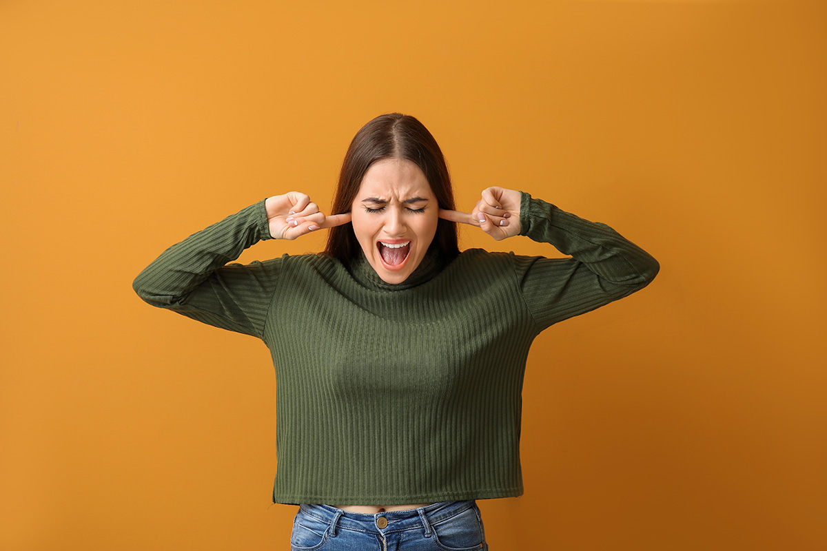 A woman putting her fingers in her ears so she cannot hear