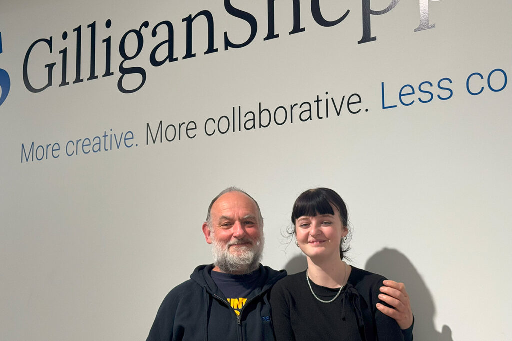 Bruce Sheppard and Antoinette Cole standing in front of Gilligan Sheppard logo