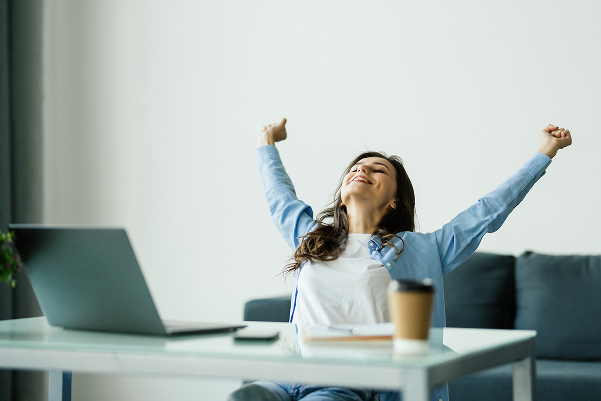 woman stretching arms in victory at desk