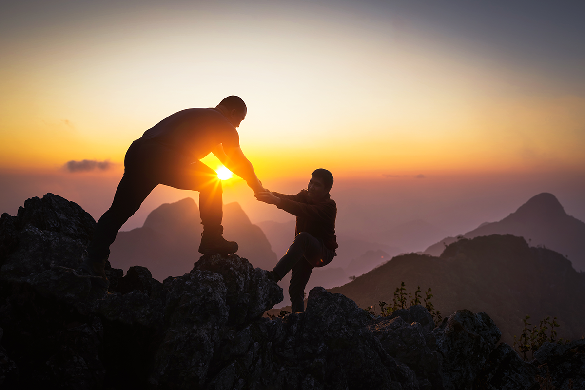 hikers partnering to climb mountain