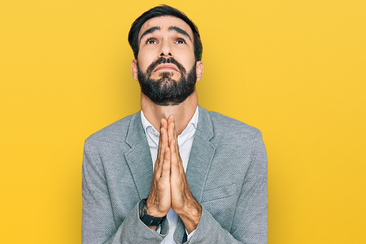 businessman dramatically pleading with hands together