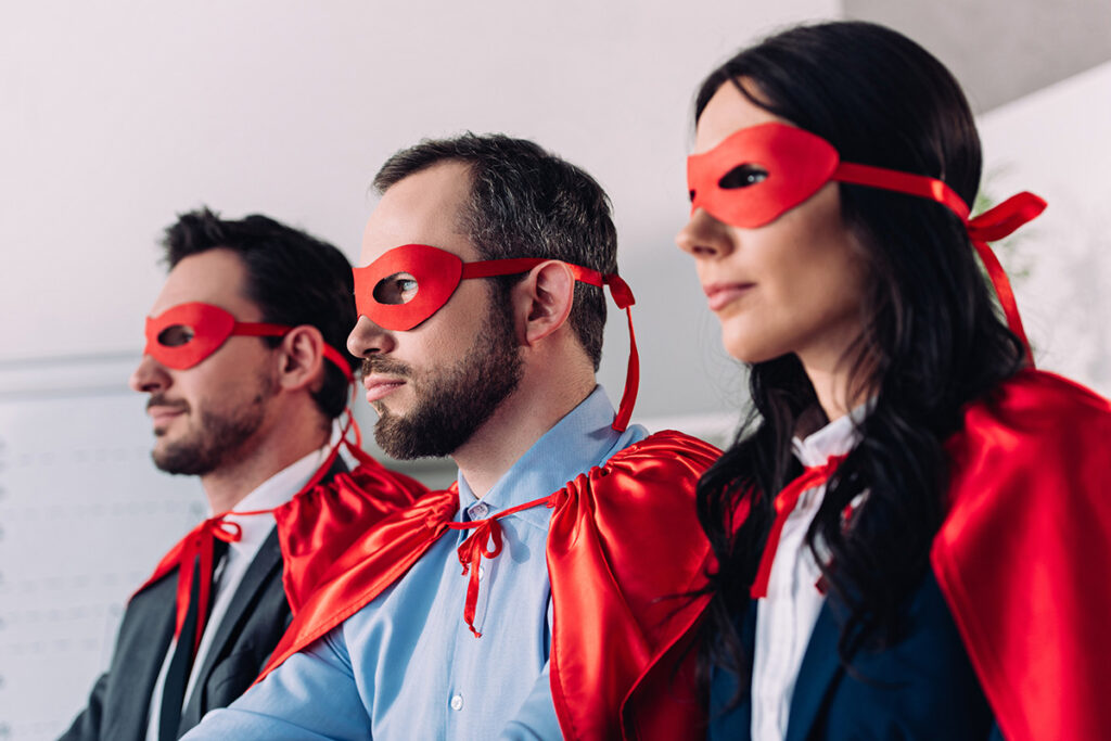 office workers wearing red capes and masks