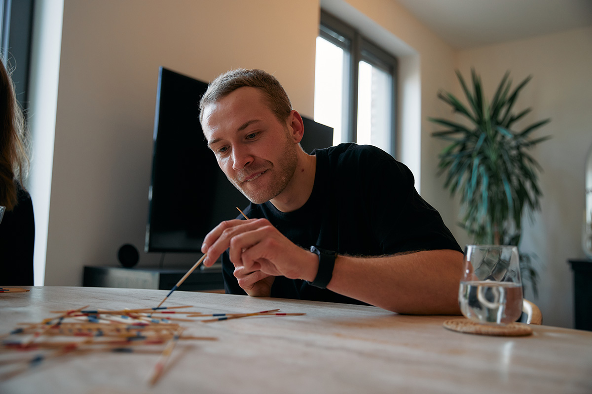 Man playing pick up sticks on dining table