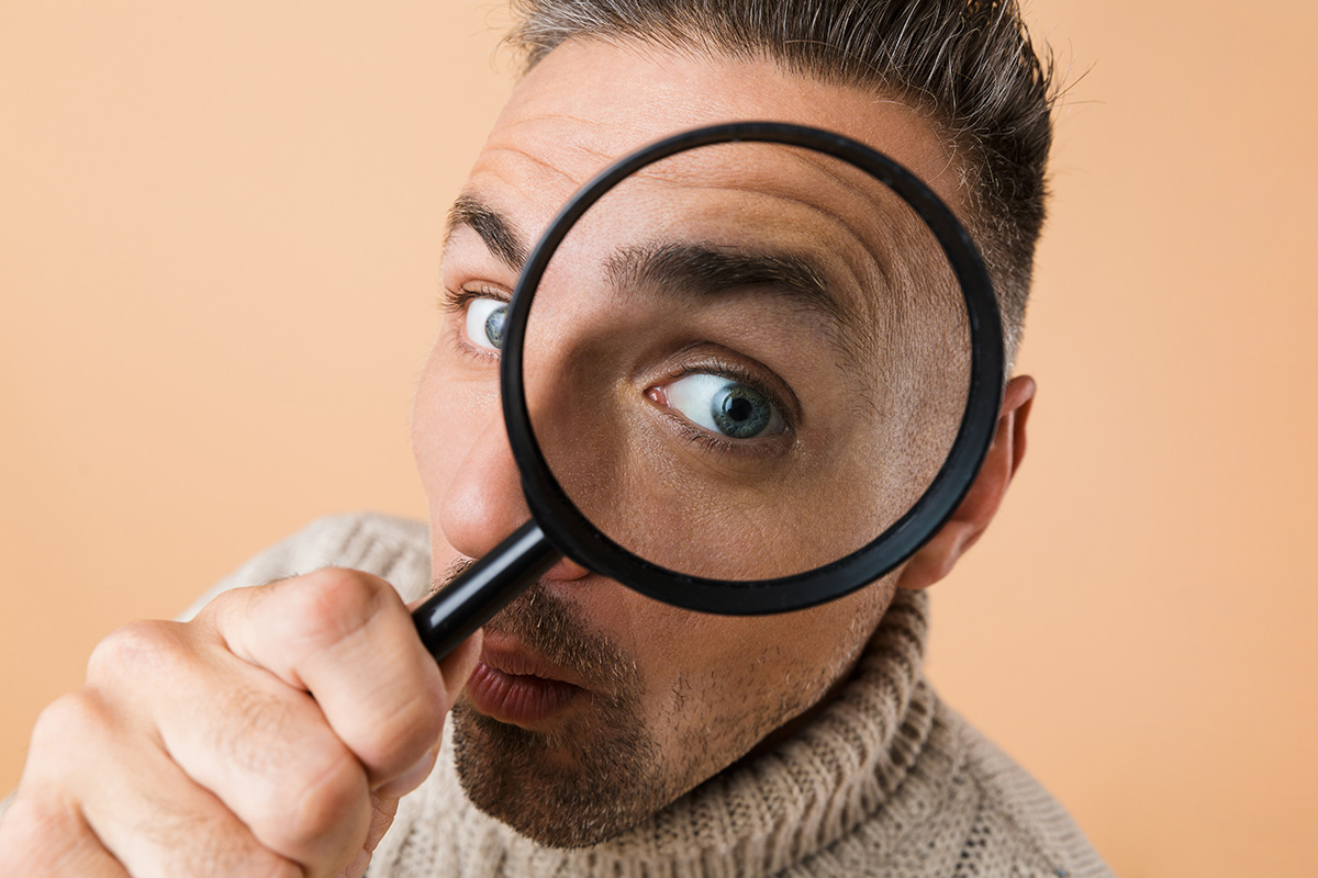 man staring through a magnifying glass